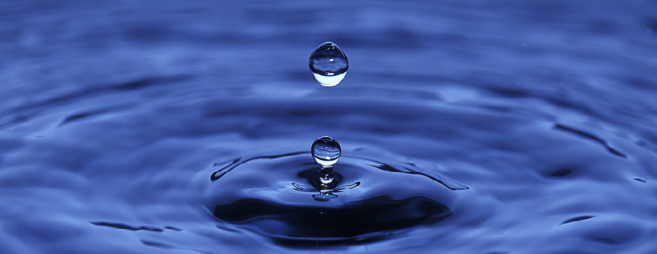 A water droplet bounces off the surface of a pool of water.