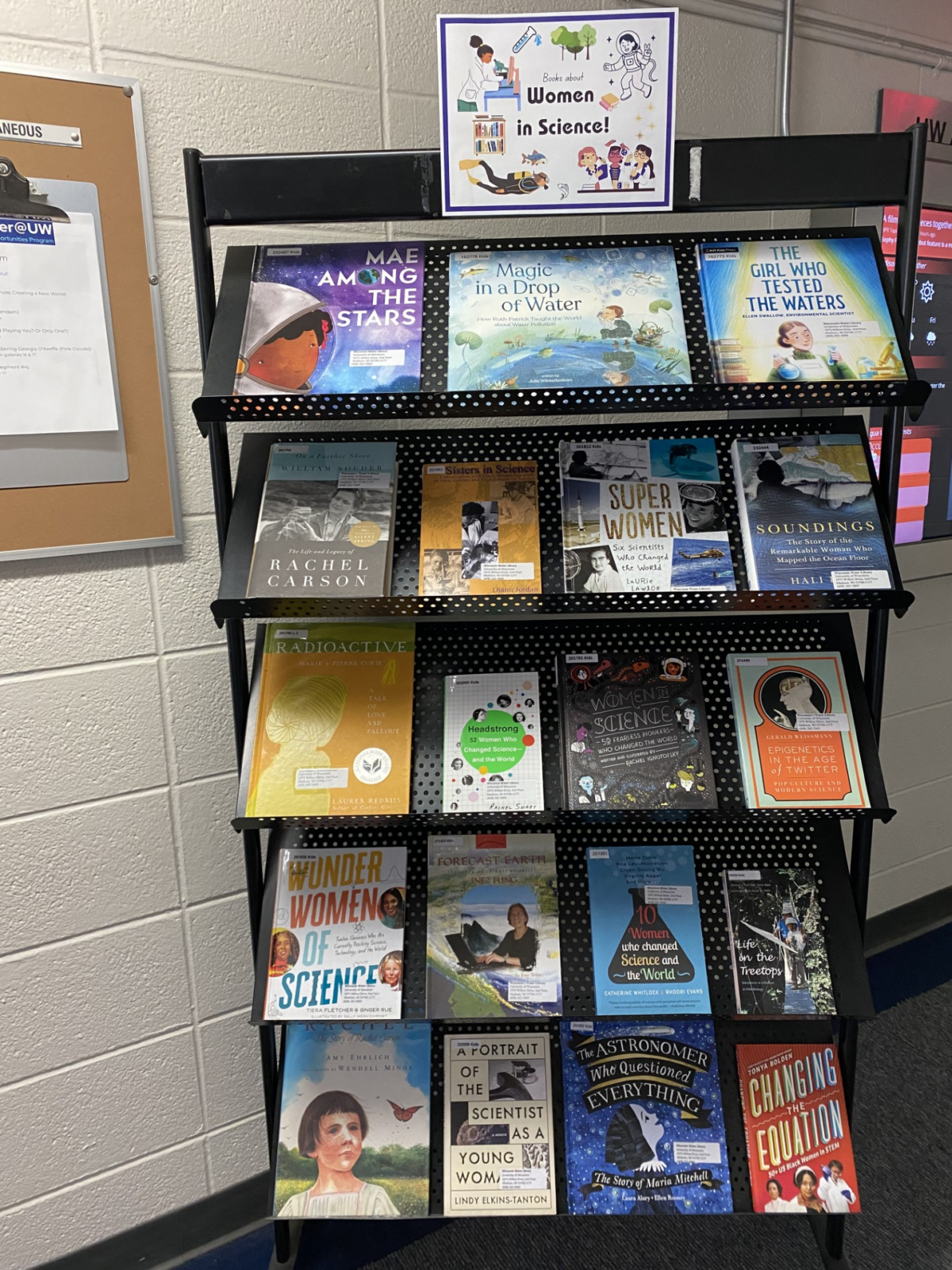 Book display on a rolling rack featuring books about women in science. Full book list is below.