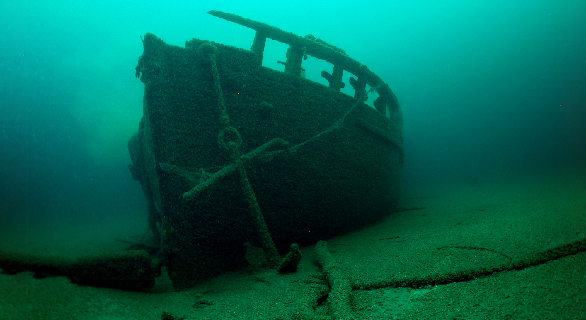 An underwater shipwreck in murky blue-green water