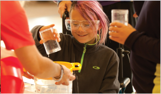 Photo of child in safety glasses pouring liquid. Photo credit: Eric Baillies

